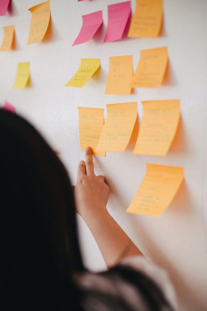 Sticky notes stuck to a wall with a person pointing to one of them in a design workshop